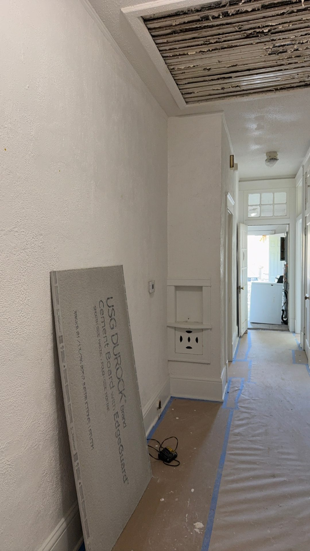 Lawrence project — hallway during renovation, floors protected and cement board staged