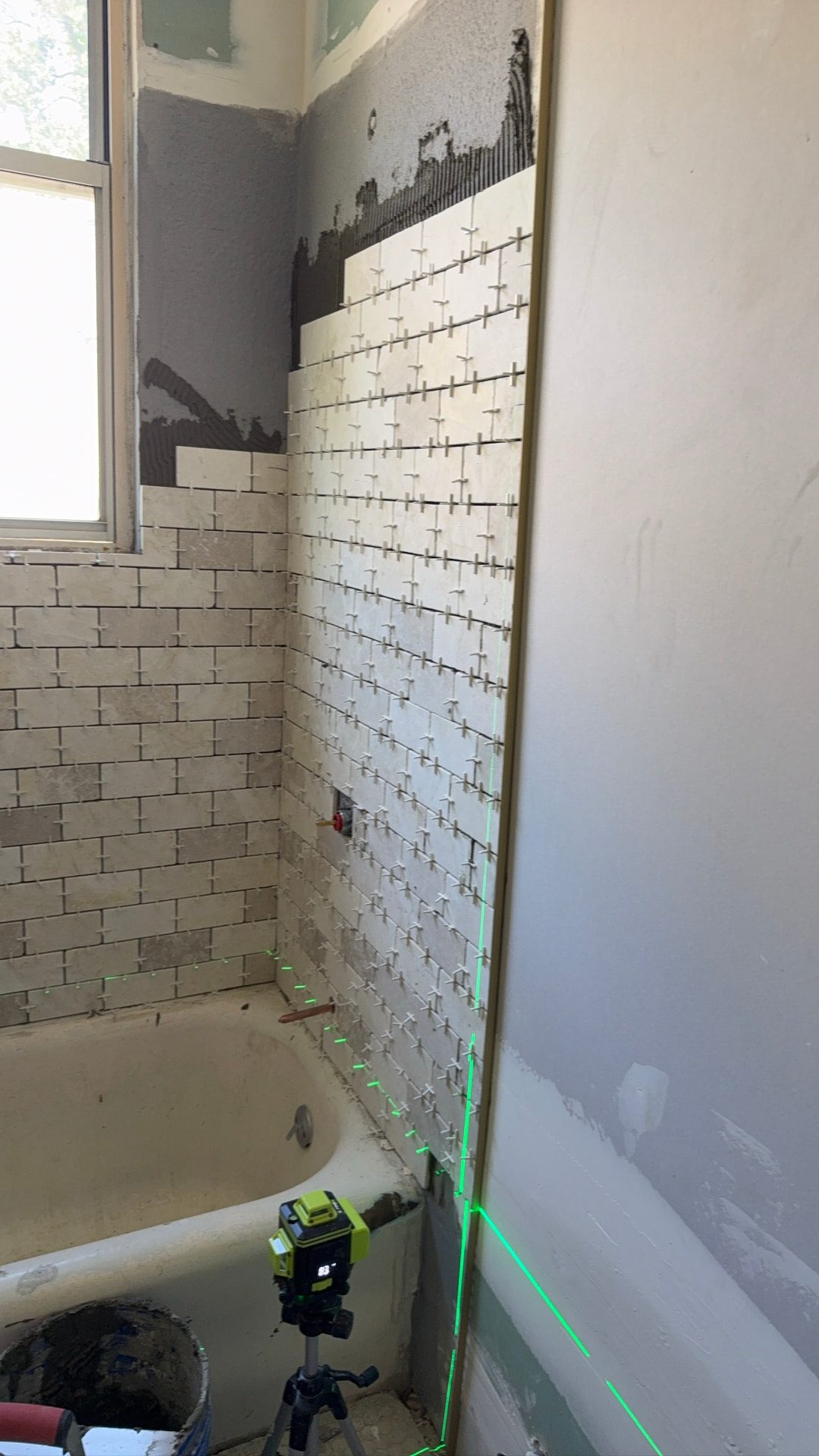 Lawrence project — bathroom tile going in over the tub, set to a laser line