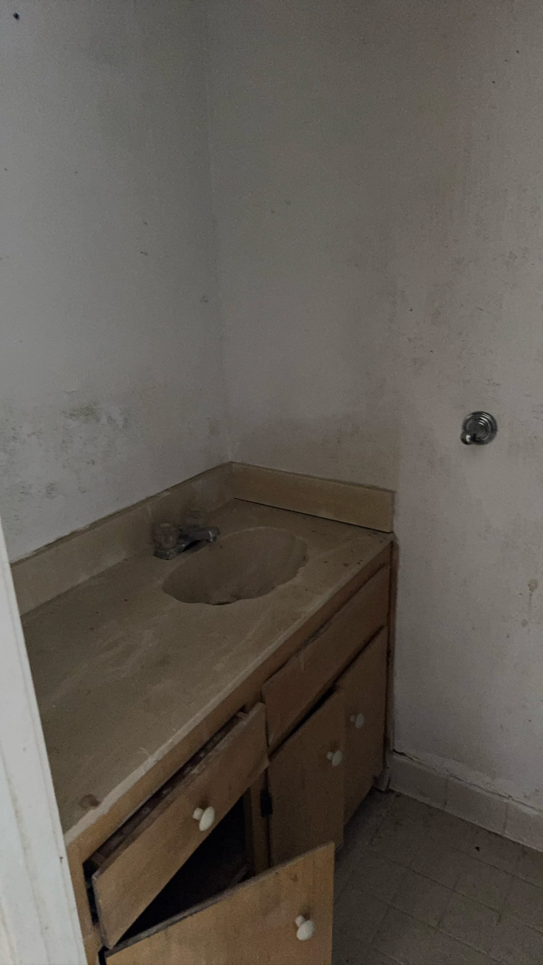 Lawrence project — bathroom vanity before renovation, damaged cabinet and stained walls