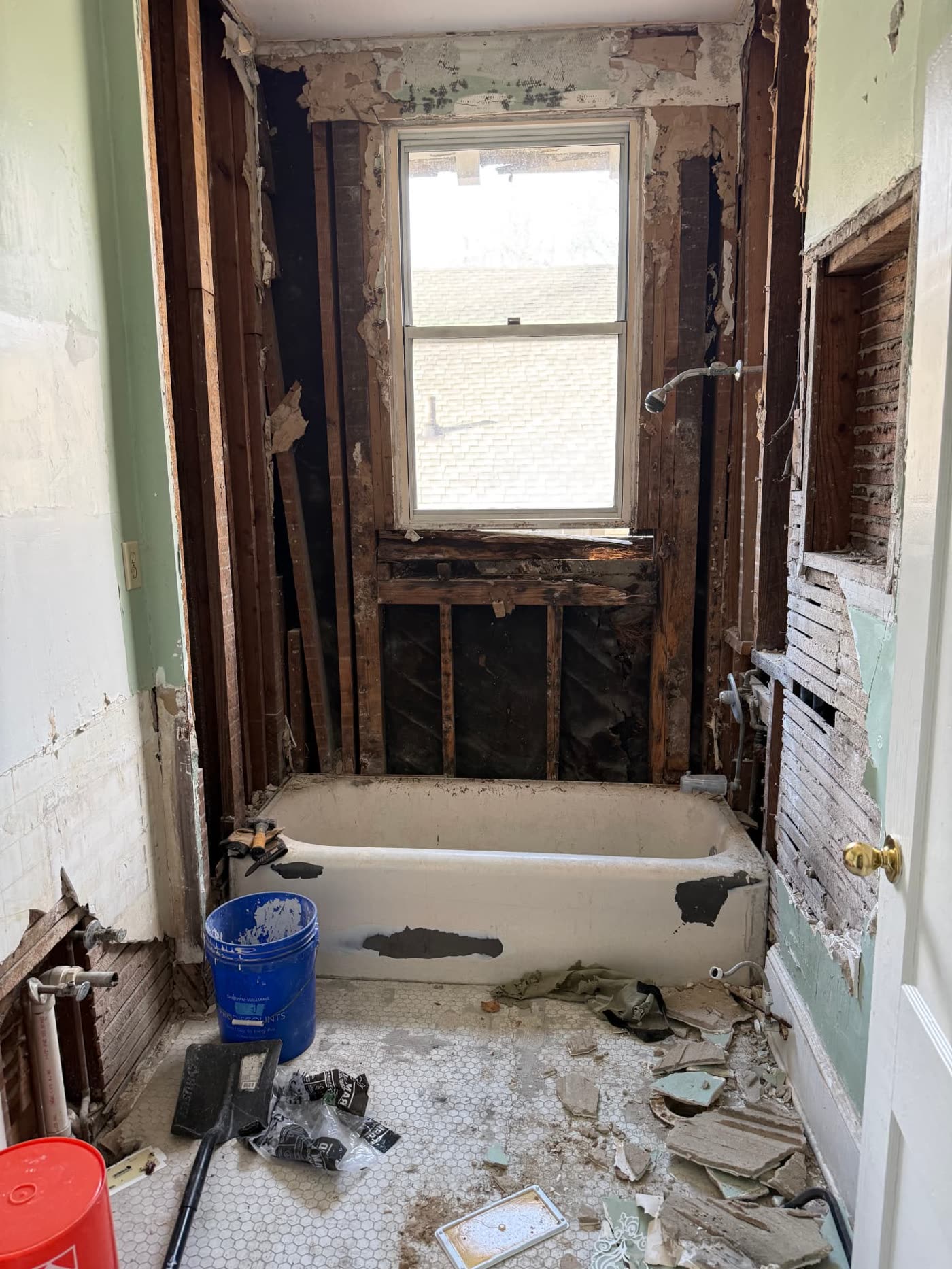 Lawrence project — bathroom stripped to the studs during renovation, original tub and radiator in place